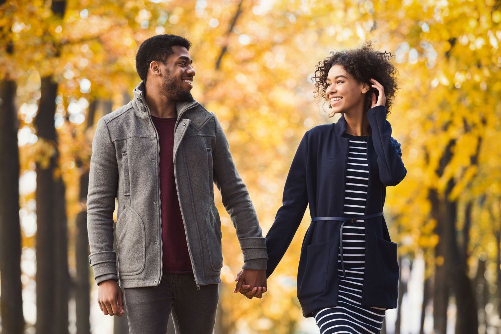 ouple in love holding hands and walking through park on sunny autumn day