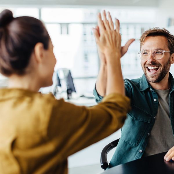 Happy people doing business, coworkers exchanging a high-five in an office