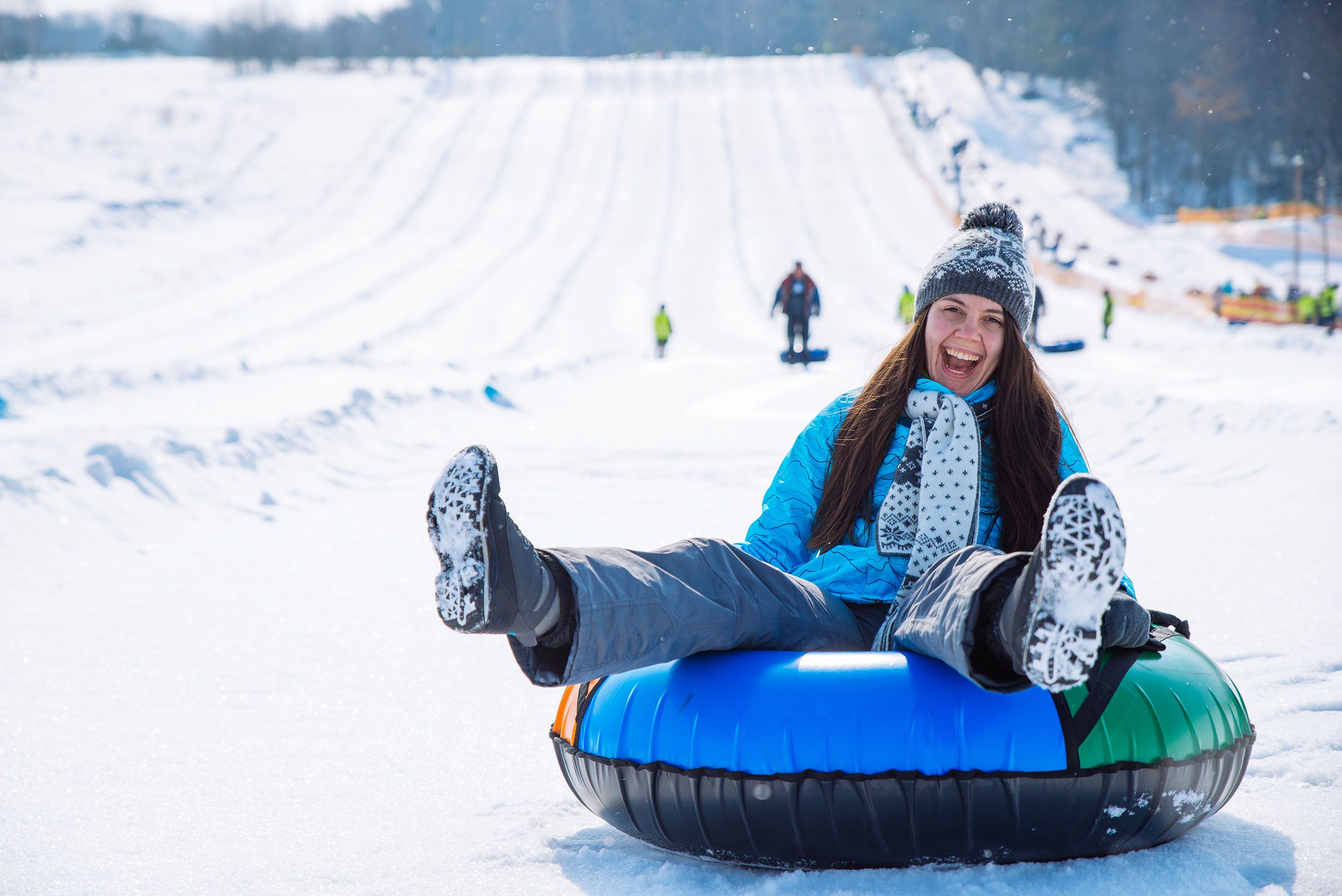 Young smiling girl snow tubing down hill in winter snow